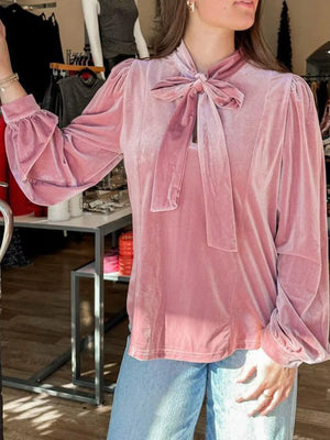 Chic velvet tie-neck blouse in dusty pink with puff sleeves and ruffled cuffs.