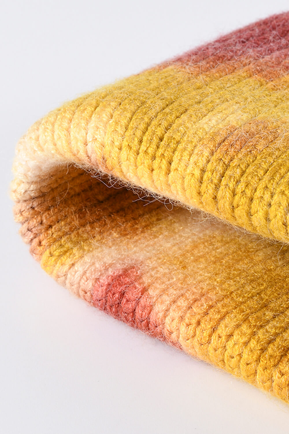 Ribbed knit beanie with a sunset dip-dye pattern in yellow, pink, and orange hues.