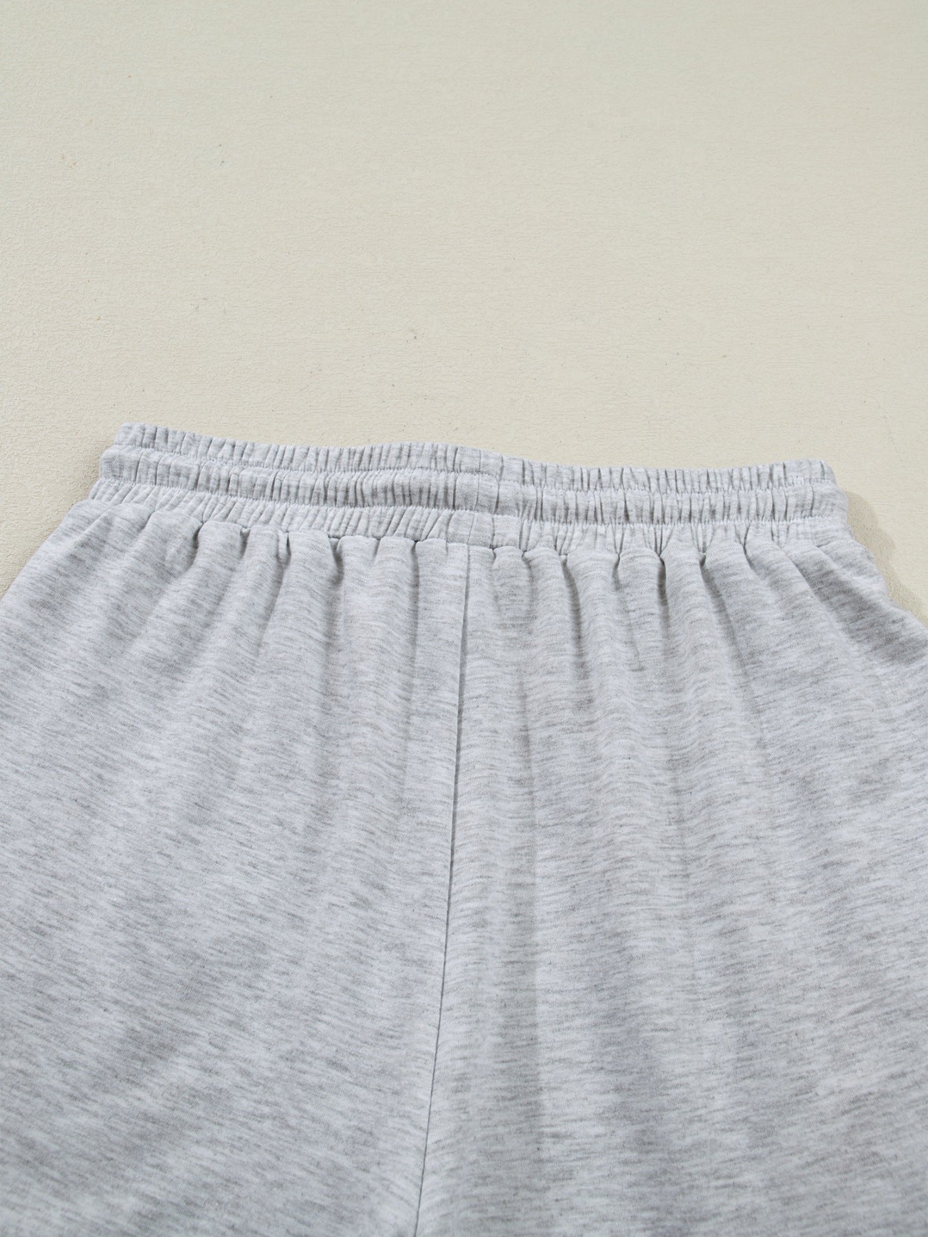 Light grey polyester lounge shorts with elastic waistband and drawstring detail.