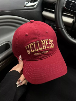 Red cotton baseball cap with gold embroidered "WELLNESS" and "Woodus & Rush" text