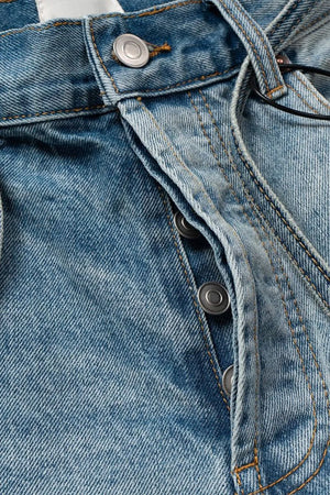 Distressed denim bermuda shorts in medium wash with button fly and tie detail.