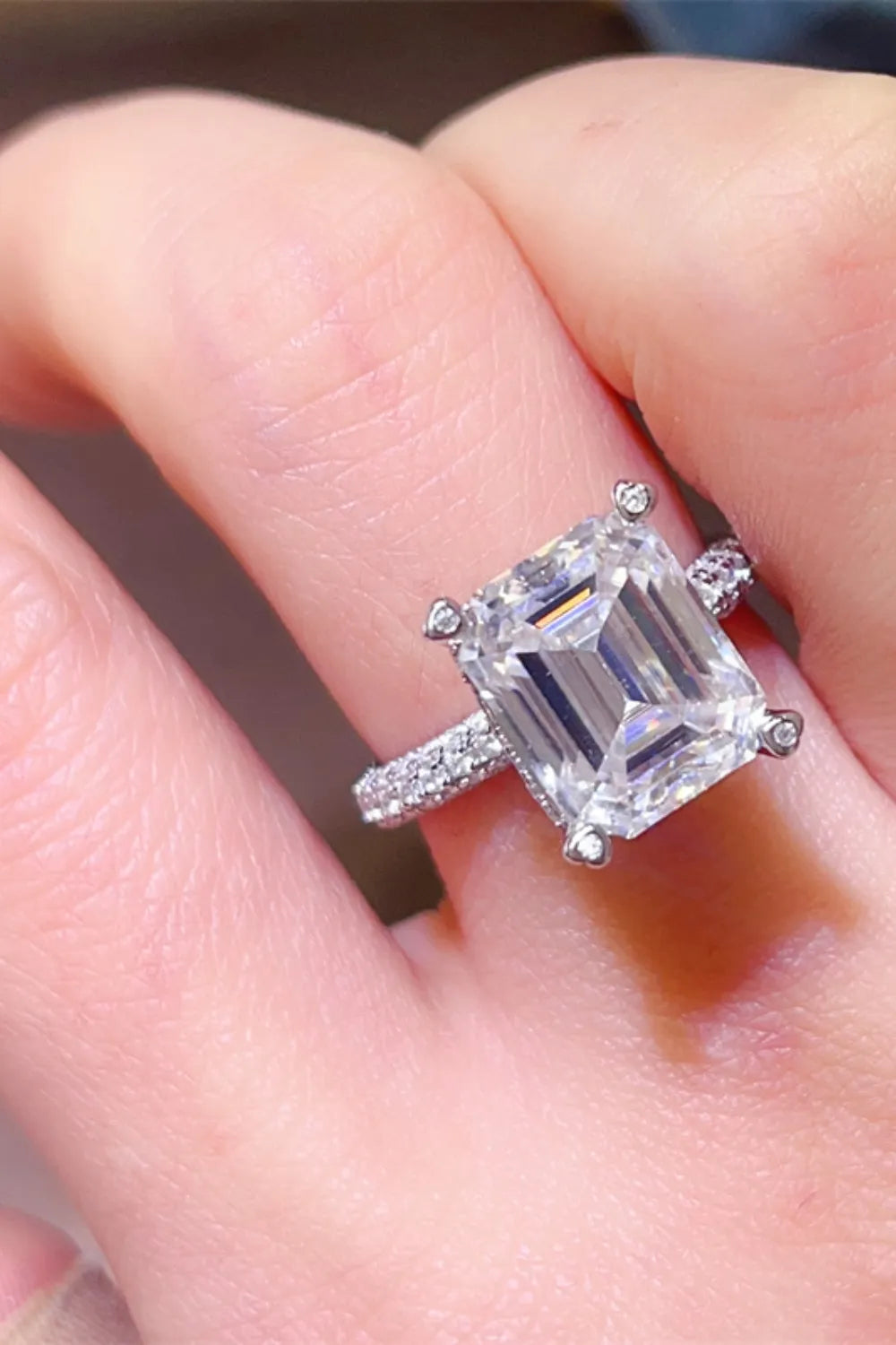 Emerald cut moissanite ring with pave band in silver.