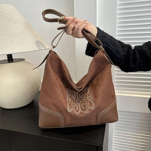 Brown suede hobo bag with contrast stitching and appliqué detail.