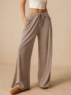 Gray ribbed wide-leg drawstring pants with pockets, styled casually.