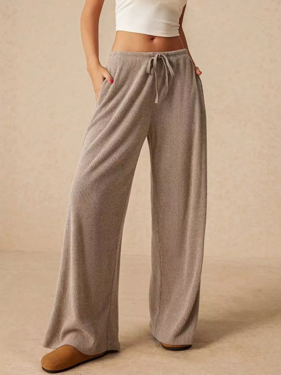 Gray ribbed wide-leg drawstring pants with pockets, styled casually.