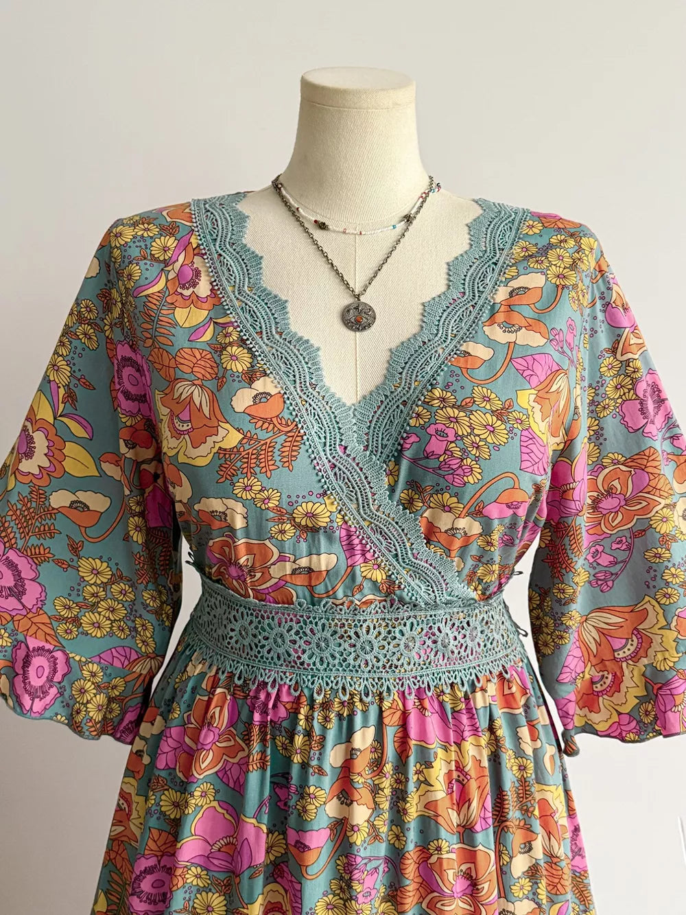 Floral lace-trimmed surplice maxi dress in teal with a vibrant floral print and boho style.