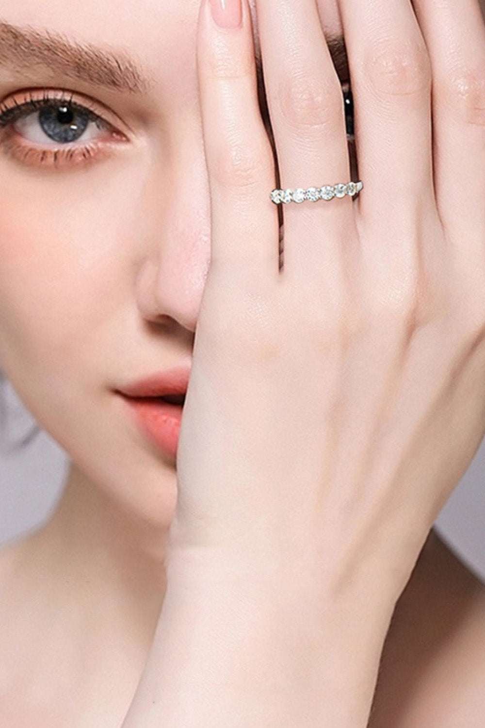 Silver band ring with seven clear stones on a woman's finger.