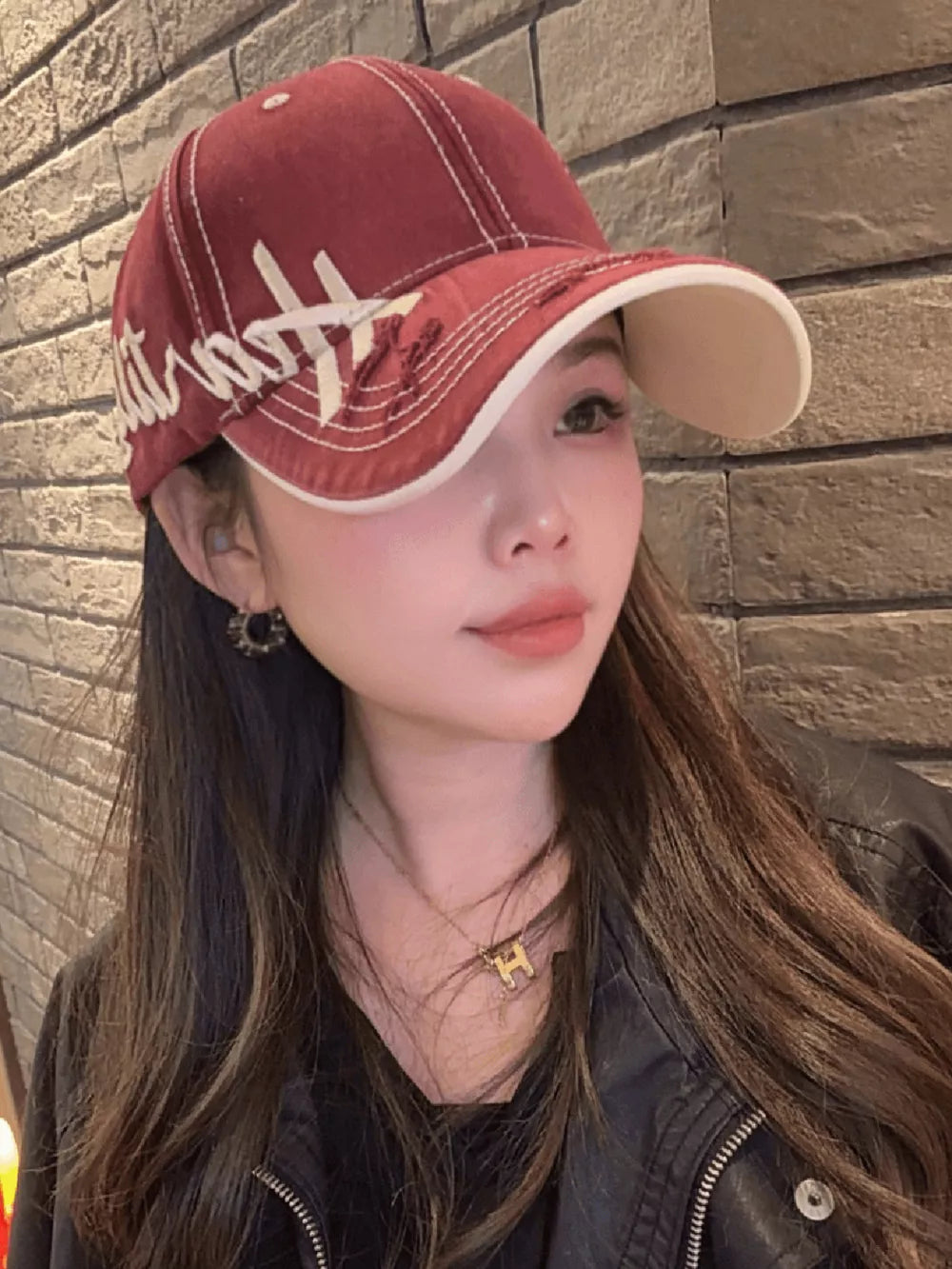 Red cotton baseball cap with white stitching and distressed embroidery detail.