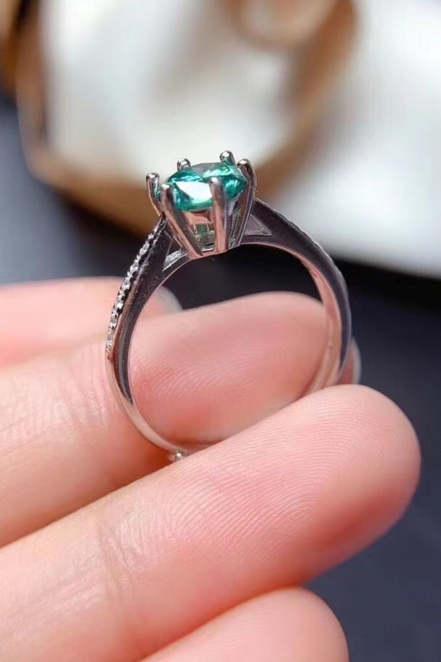 Teal moissanite solitaire ring with pave band in sterling silver.