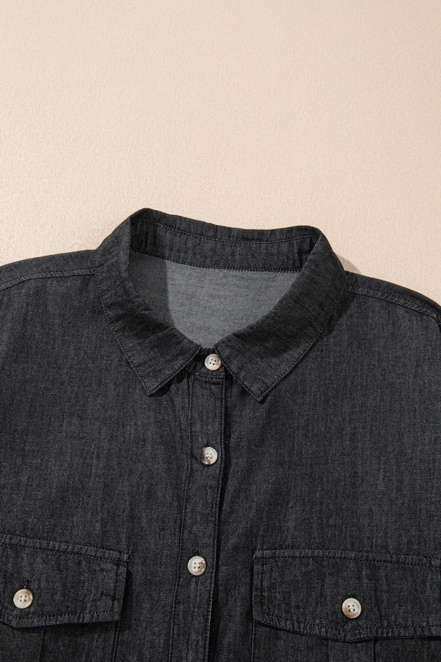 Relaxed black denim shirt with buttoned patch pockets and collar detail.