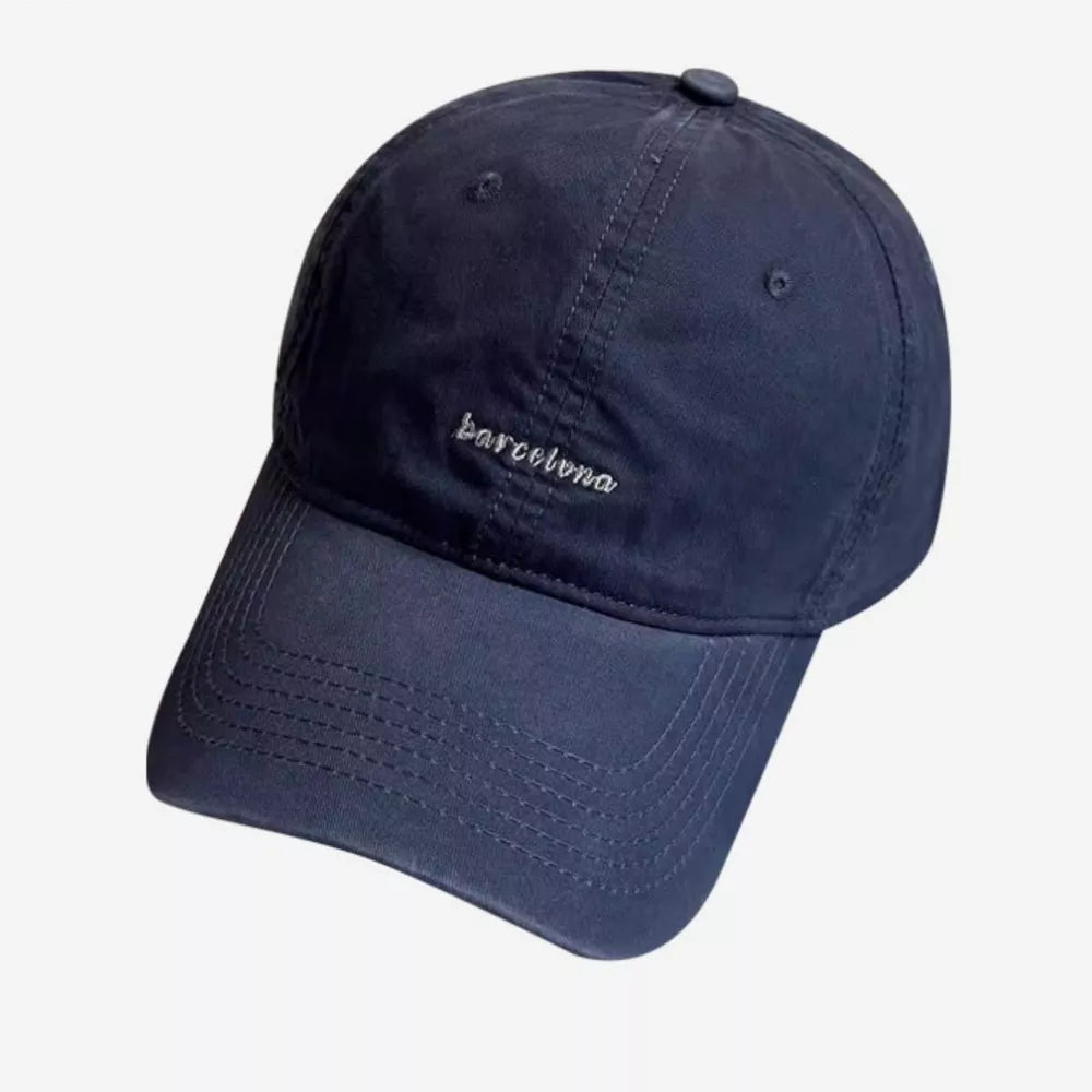 Navy baseball cap with embroidered "barcelona" text and stitched brim.