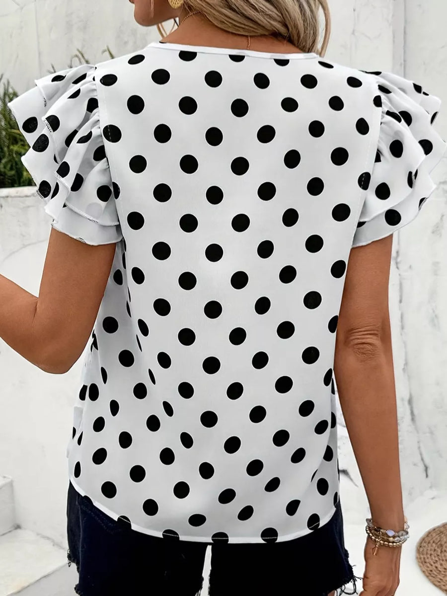 White polka dot blouse with ruffled short sleeves and a round neckline.