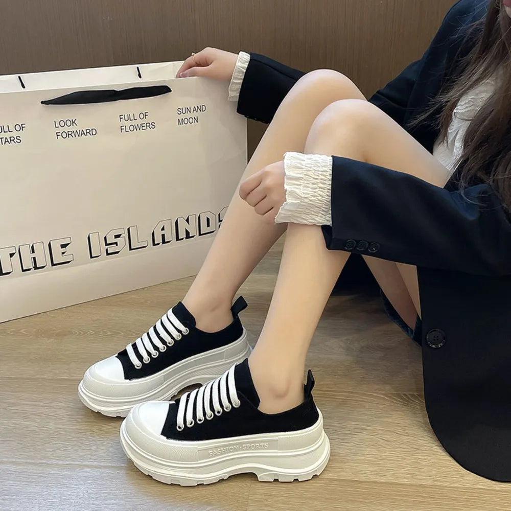 Black canvas platform sneakers with white laces and thick white soles.