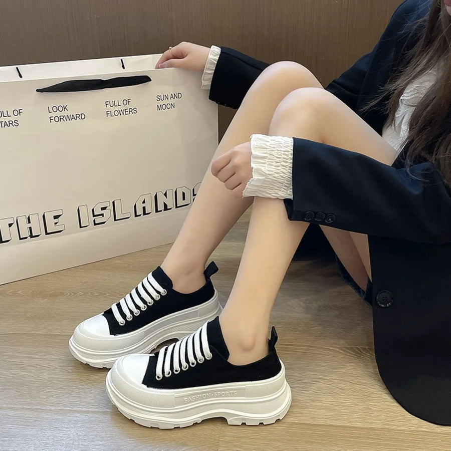 Black canvas platform sneakers with white laces and thick white soles.