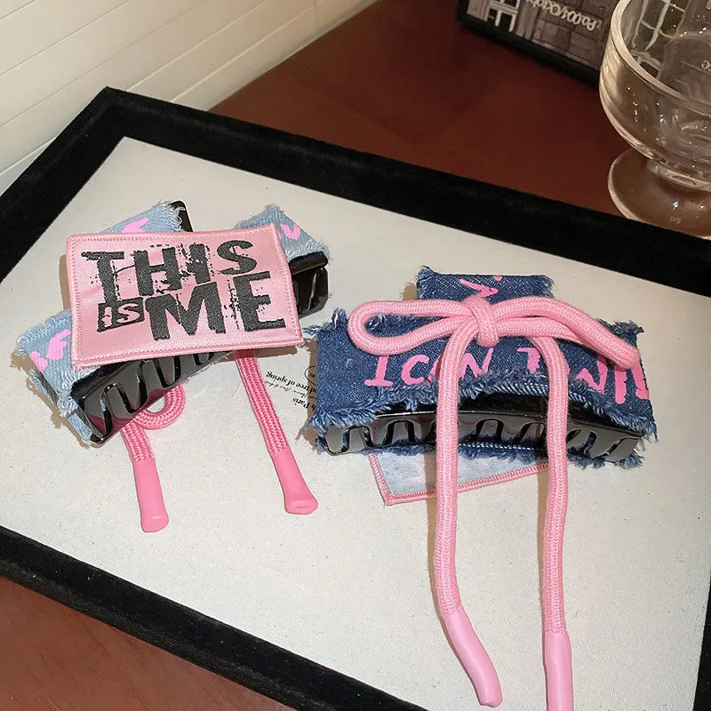 Denim patchwork claw clip with pink drawcord and text detail.