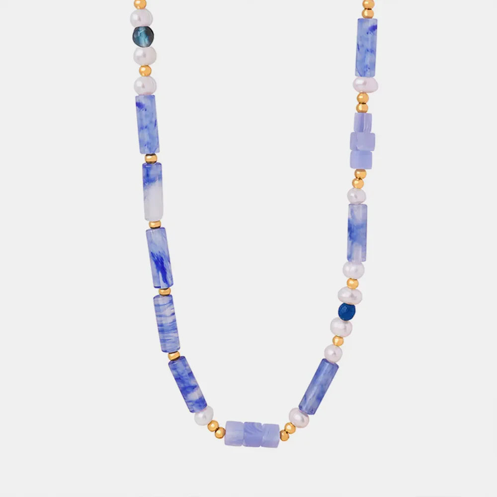 Lapis lazuli and pearl bead necklace with gold accents in light blue.