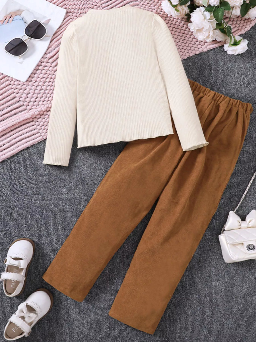 Apricot ribbed long sleeve top with ruffled hem and corduroy pants.