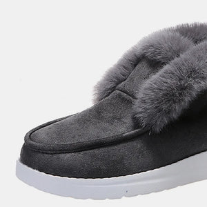 Dark gray suede slip-on booties with plush shearling lining and white sole.