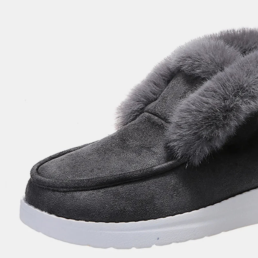 Dark gray suede slip-on booties with plush shearling lining and white sole.