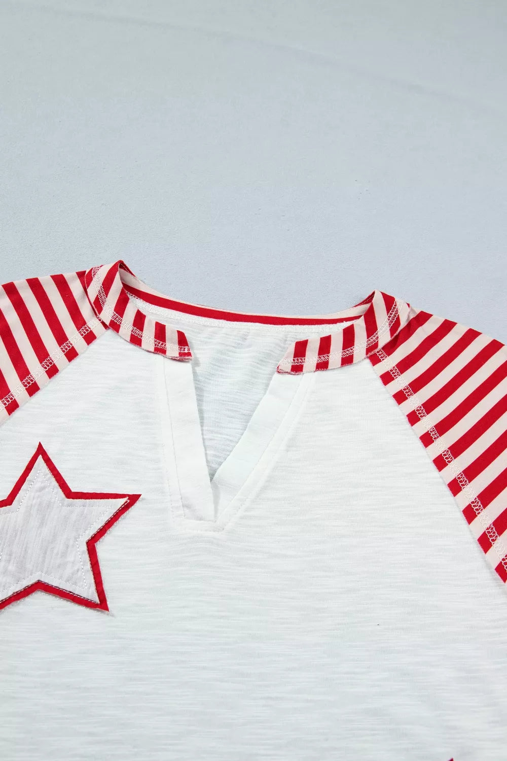 White t-shirt with red striped raglan sleeves, V-neck, and a star applique.
