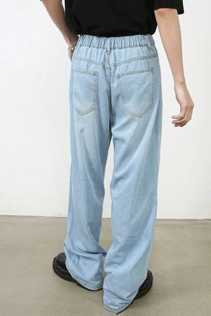 Light wash denim jeans with a relaxed fit and wide leg, featuring an elastic waistband and back pockets.