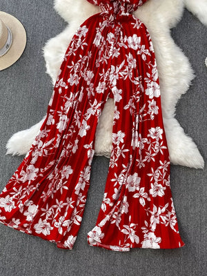 Red floral pleated wide-leg romper with smocked waist and flowy cotton fabric.