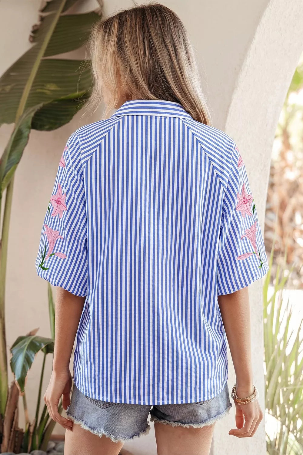 Blue and white striped button-down shirt with pink floral embroidery on the sleeves.