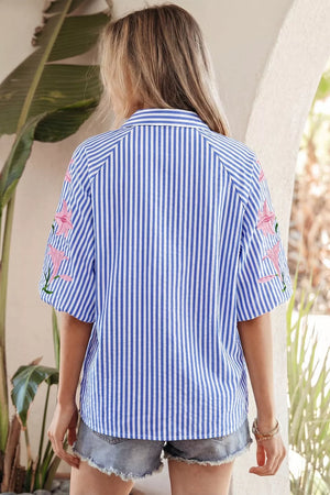 Blue and white striped button-down shirt with pink floral embroidery on the sleeves.