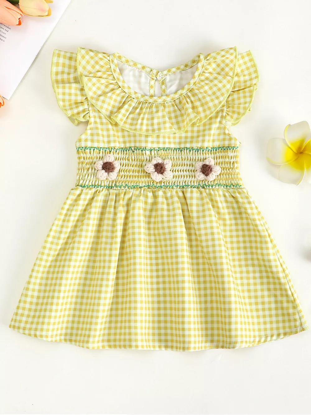 Yellow gingham baby dress with ruffled collar, smocked waist and floral embellishments.