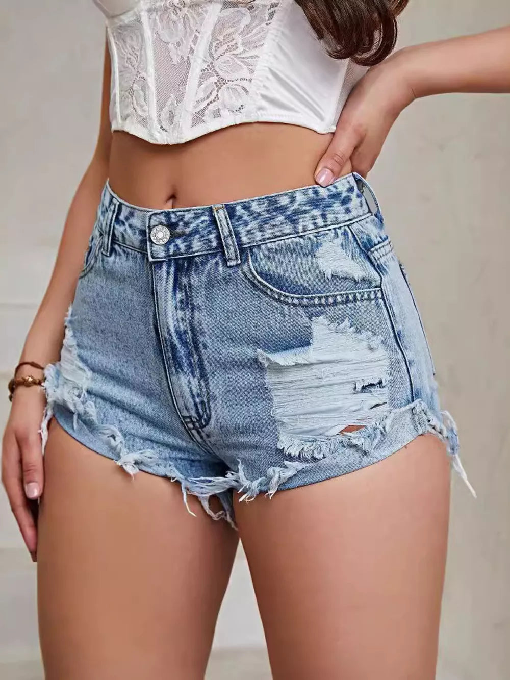 High-waisted distressed denim shorts in Vintage Washed Blue with frayed hem and rips.