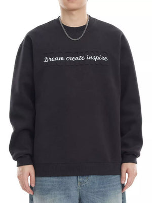 Black oversized crew-neck sweatshirt with embroidered "Dream create inspire" text