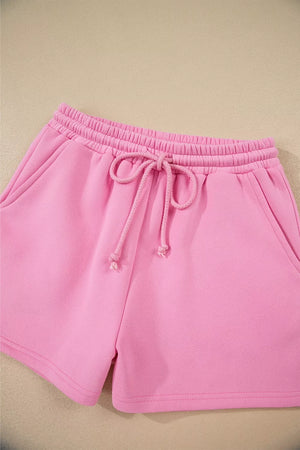 Pink cotton shorts with elastic waistband and drawstring, side pockets.