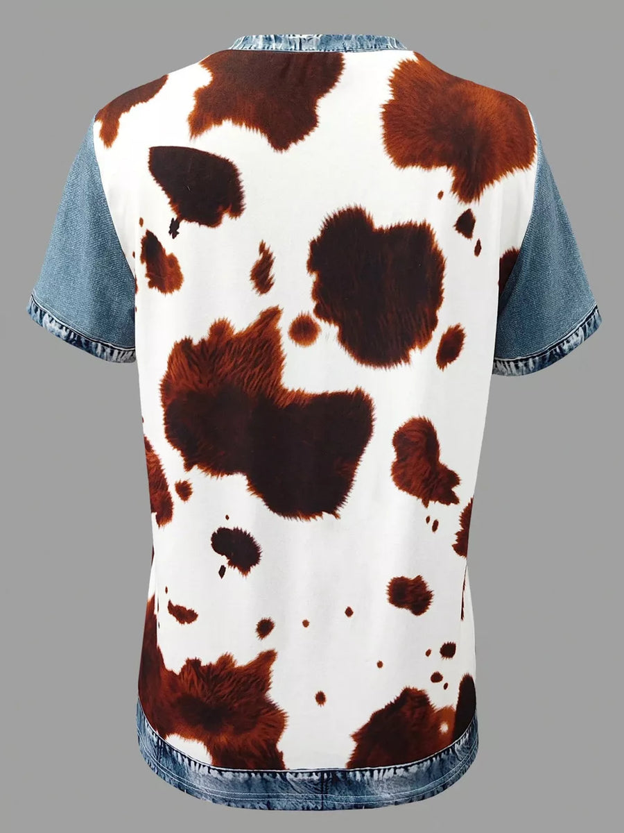 Denim patchwork blouse with cow print body and short sleeves.