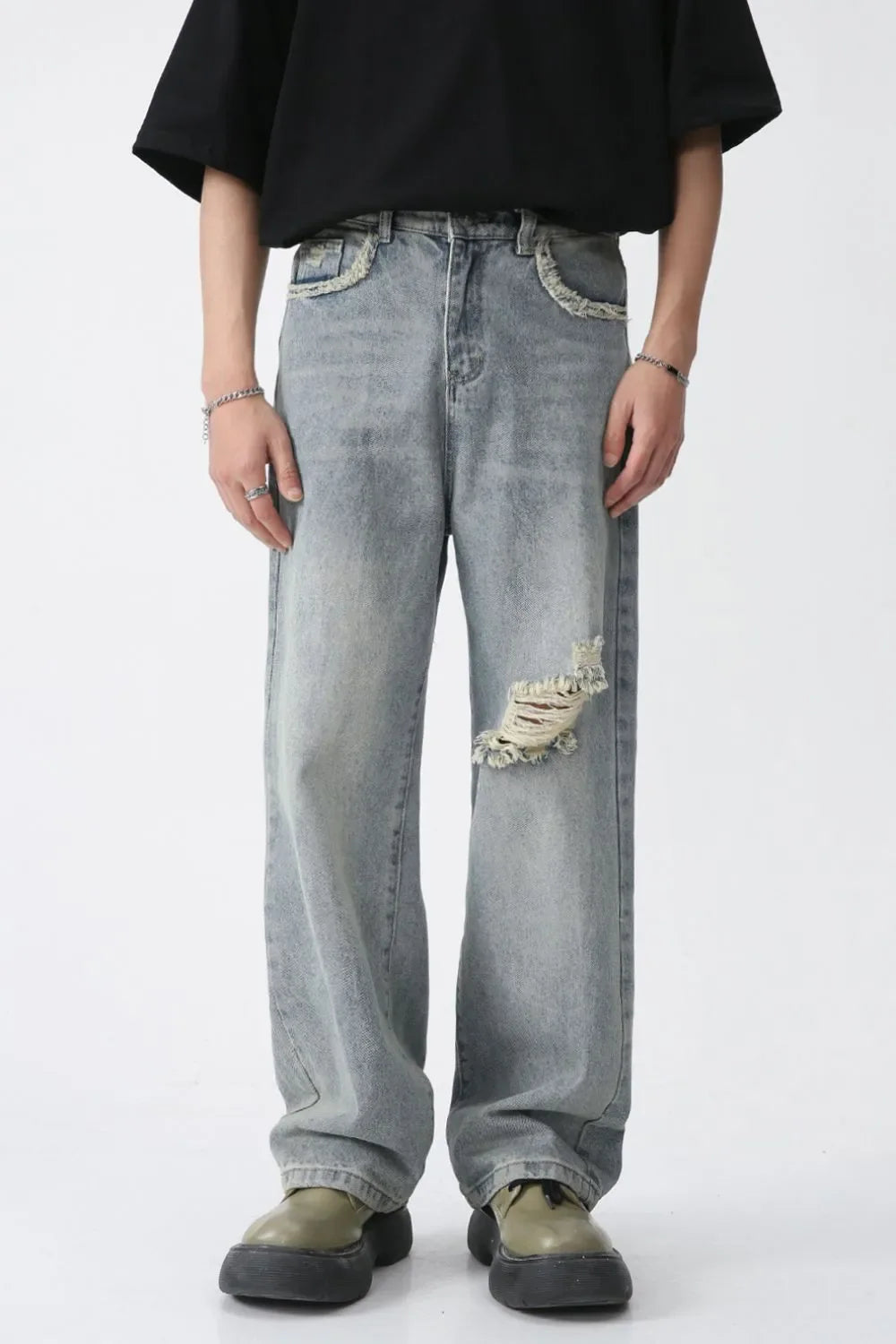 Distressed wide-leg denim jeans in medium wash with raw edge pockets and a knee rip.