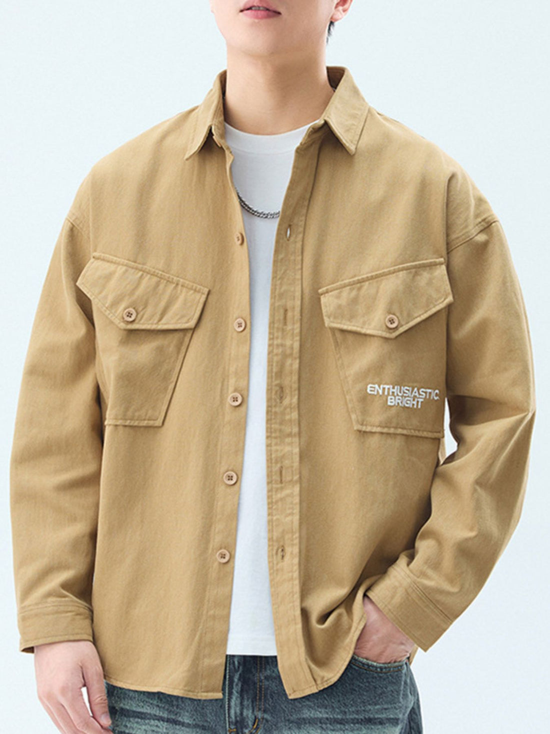 Men's tan cotton casual button-up shirt with chest pockets and embroidered text.
