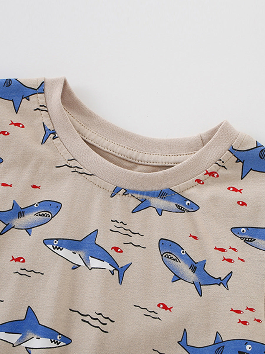 Toddler crew neck t-shirt with allover blue shark and red fish print on beige fabric.