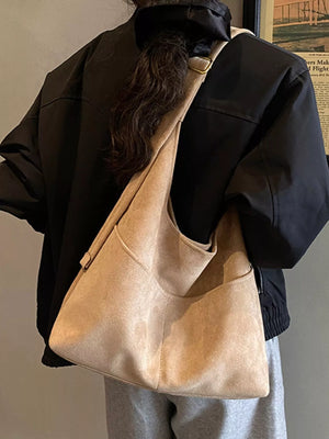 Khaki suede shoulder bag with exterior pockets worn by a model.