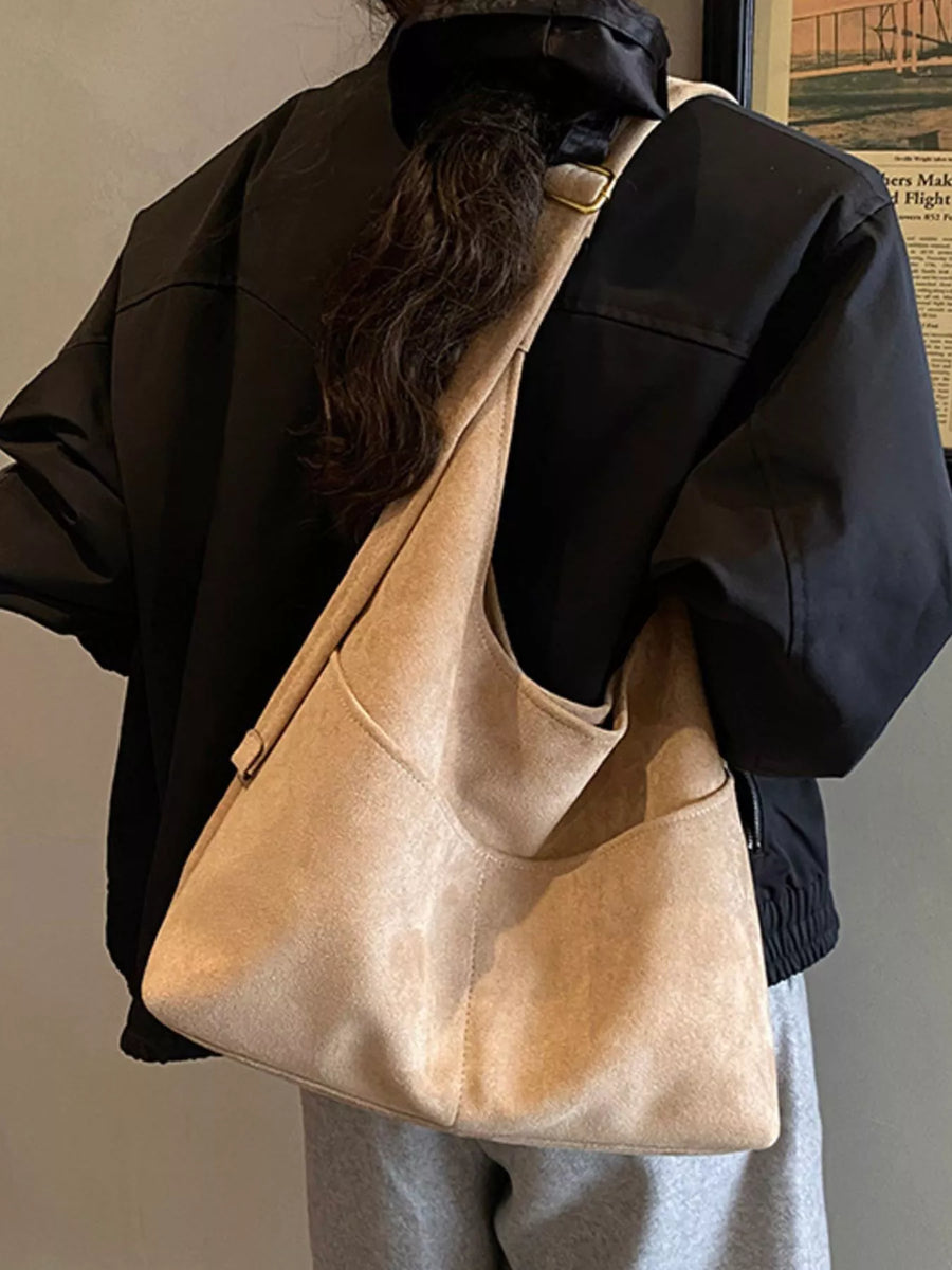 Khaki suede shoulder bag with exterior pockets worn by a model.