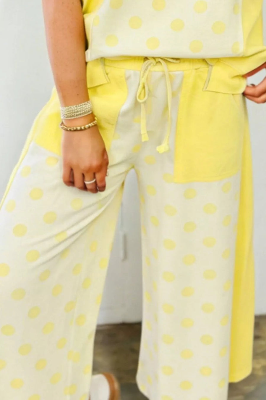 Yellow polka dot cotton blend wide leg pants with drawstring waist and color block detail.