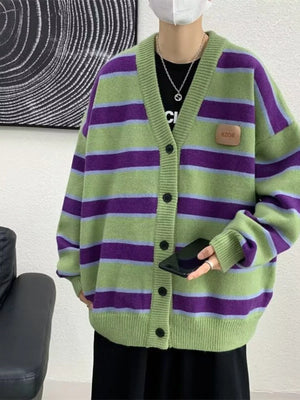 Oversized striped V-neck cardigan in green with purple and light blue stripes, featuring a buttoned front and a faux leather