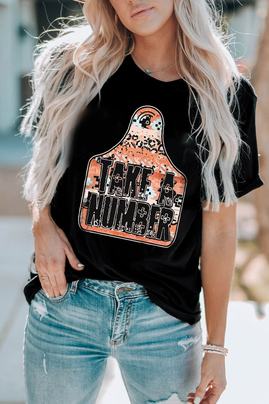 Black graphic t-shirt with "Take A Number" text on a tag design with leopard and camouflage print.