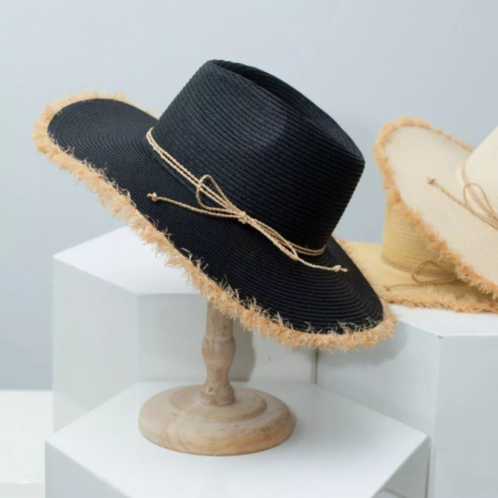 Black straw sun hat with frayed brim and twine bow detail