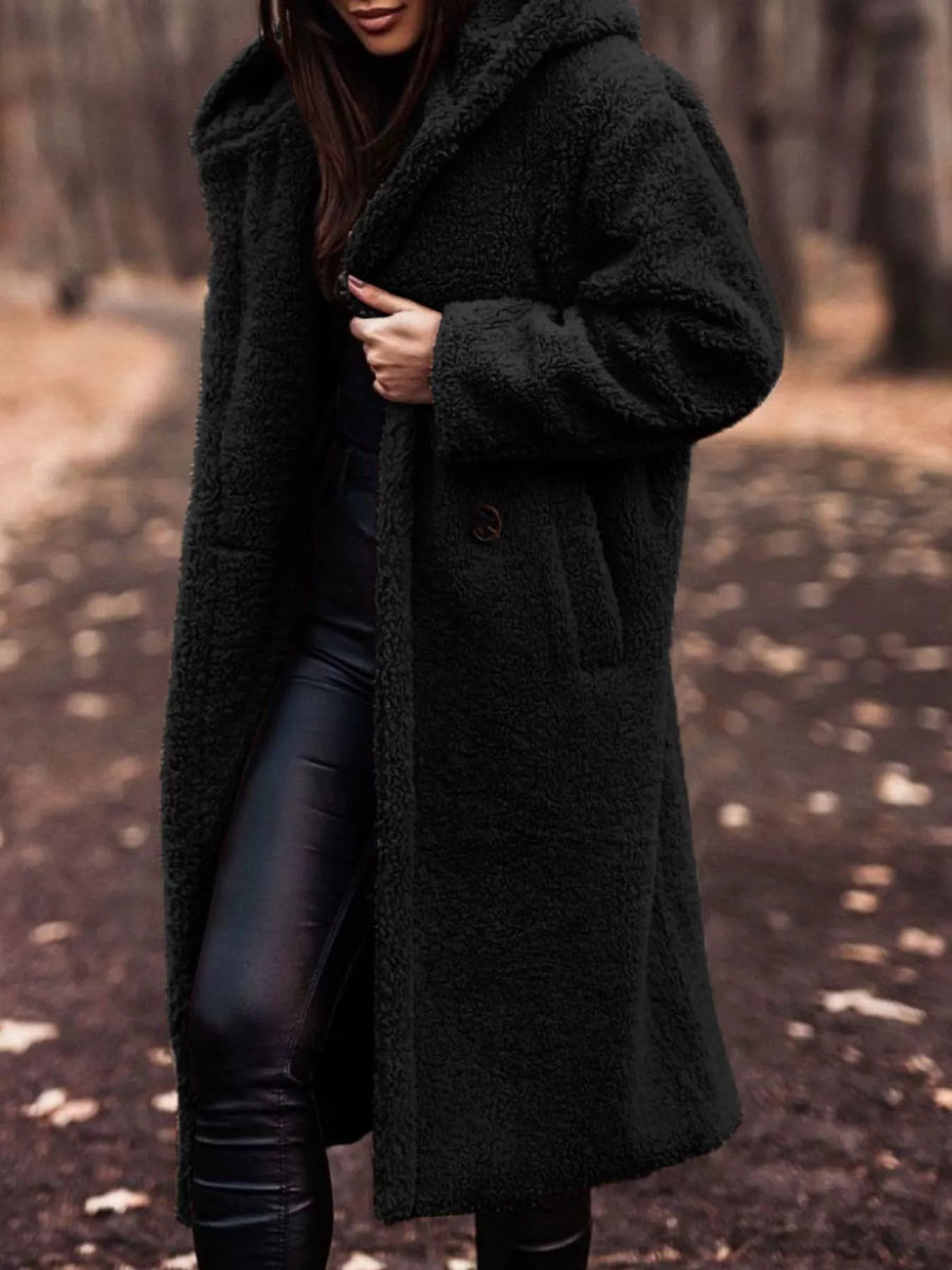 Black teddy bear longline coat with hood and button closure, worn by a woman.
