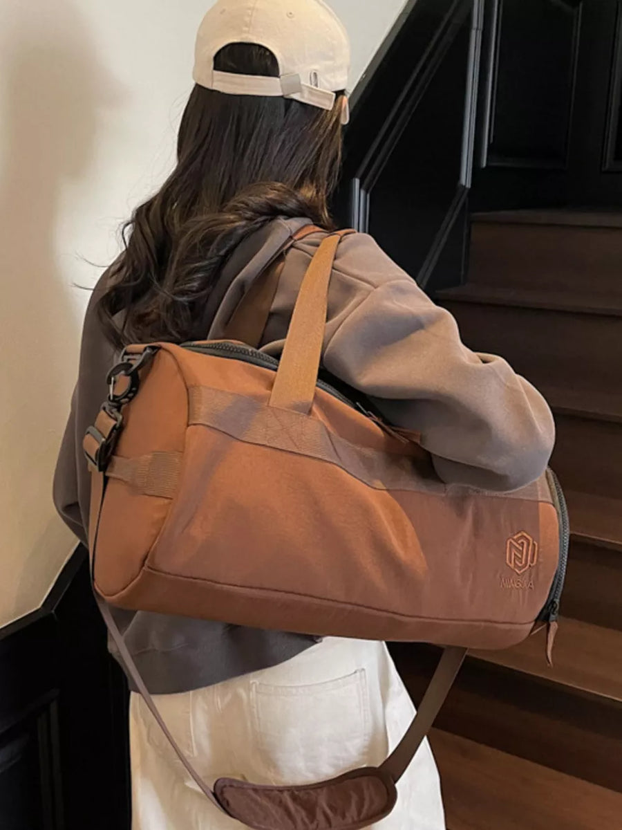 Brown Oxford cloth duffel bag with adjustable strap and carry handles, worn by a woman.