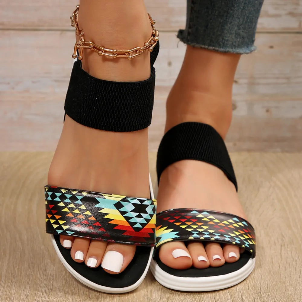 Geometric print elastic strap sandals with black ankle straps and multicolor Aztec pattern.