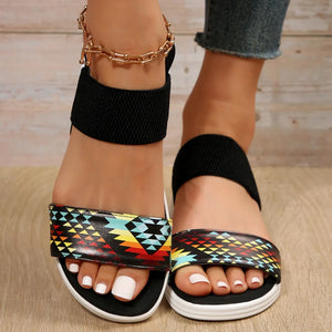 Geometric print elastic strap sandals with black ankle straps and multicolor Aztec pattern.