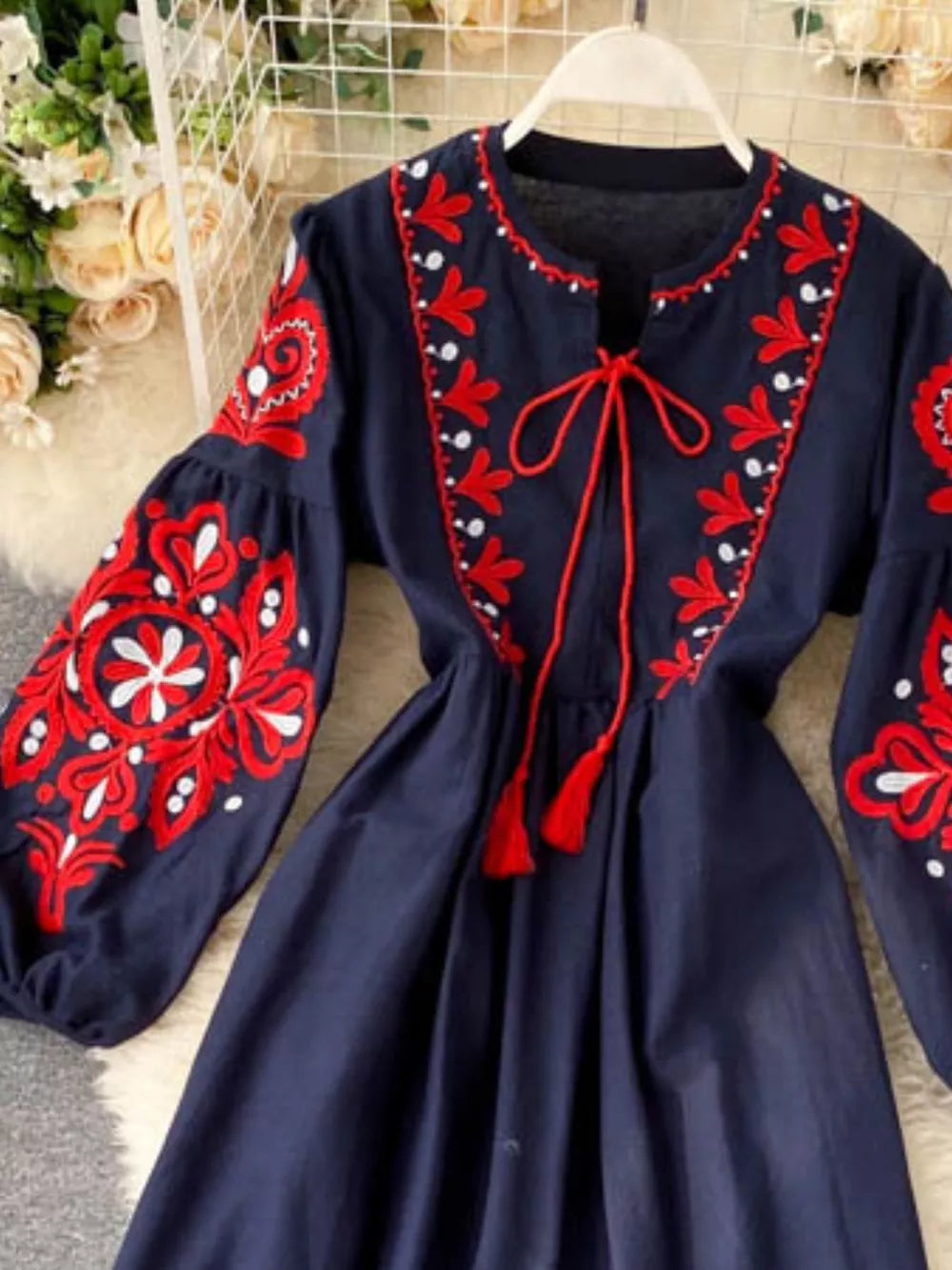 Navy blue maxi dress with red and white embroidery, balloon sleeves, and tassel tie.