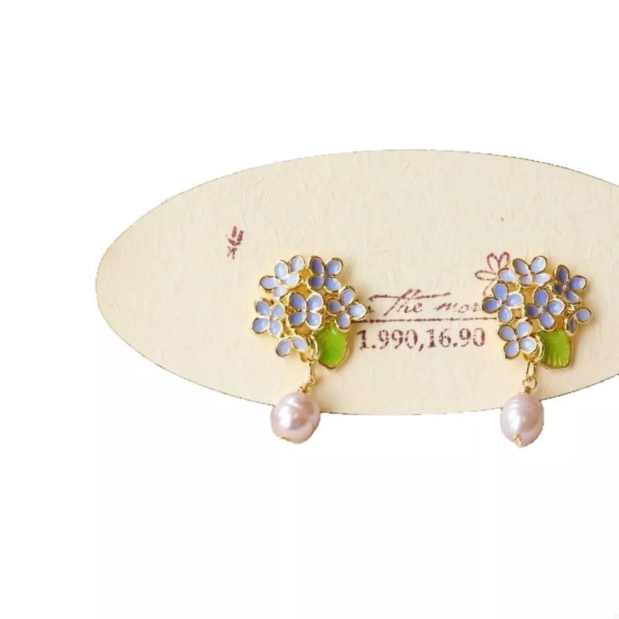 Floral pearl drop earrings with light blue flowers and green leaves.