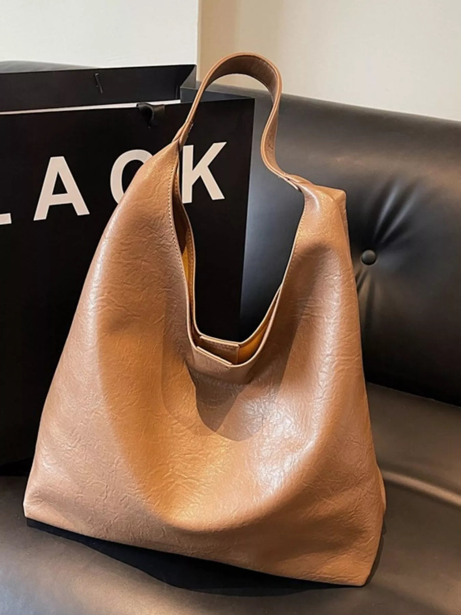 Brown sculptural PU leather tote bag with a slouchy silhouette and single strap.