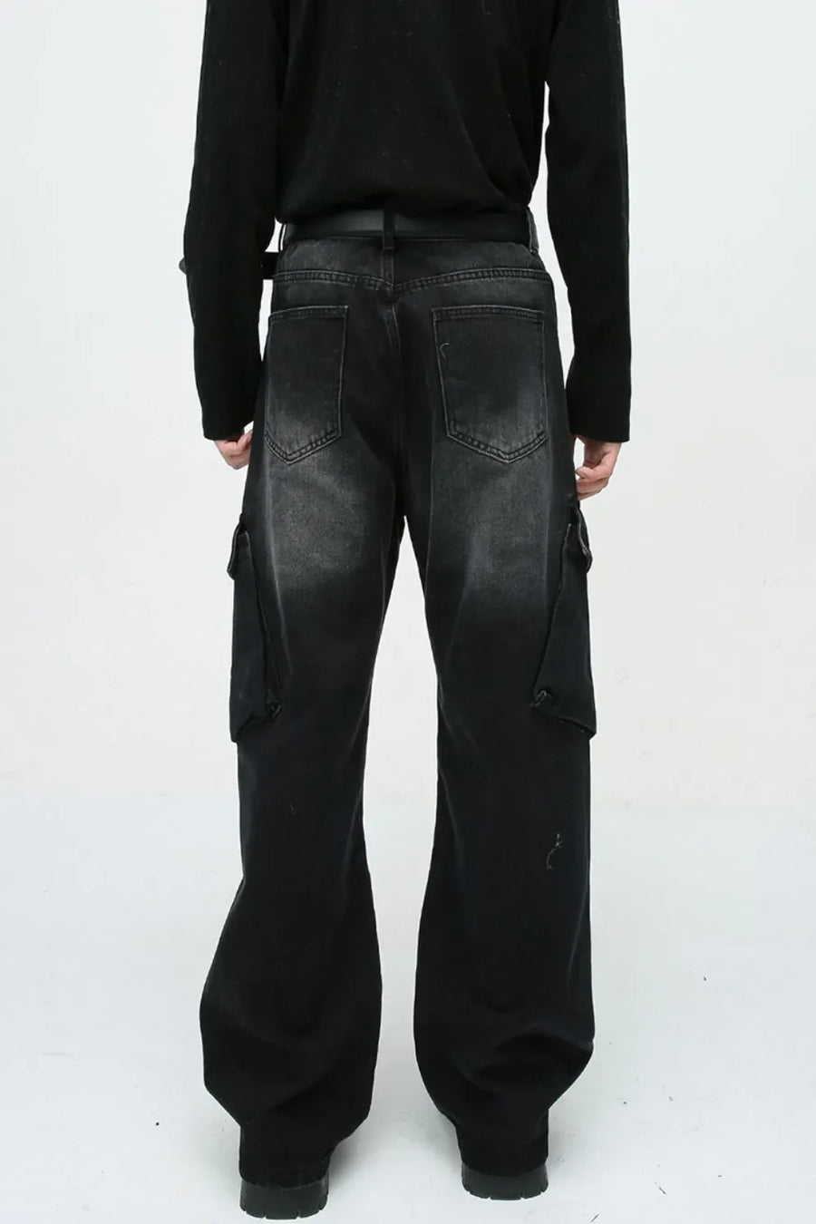 Baggy black denim cargo pants with zipper pockets and a faded wash.